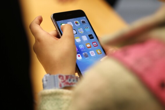 FILE - A child holds an iPhone at an Apple store on Sept. 25, 2015 in Chicago. Parents — and even some teens themselves — are growing increasingly concerned about the effects of social media use on young people. (AP Photo/Kiichiro Sato, File)