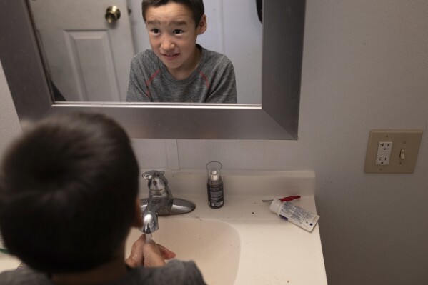 Blake Nose, 8, washes his hands inside the family household bathroom, Thursday, Aug. 17, 2023, in Akiachak, Alaska. Most of the village's nearly 700 people are getting modern plumbing for the first time this spring and summer — and finding their lives transformed. (AP Photo/Tom Brenner)