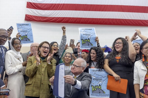 Partidarios, políticos y autores de la ley celebran luego de que el gobernador de Minnesota, Tim Walz (centro), promulga la ley “Licencia de conducir para todos”, en St. Paul, Minnesota, el 7 de marzo de 2023. (Elizabeth Flores/Star Tribune vía AP)