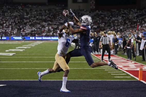 FILE - Arizona wide receiver Tetairoa McMillan (4), right, catches a touchdown pass in front of UCLA defensive back John Humphrey during the second half of an NCAA college football game Saturday, Nov. 4, 2023, in Tucson, Ariz. One of the highest-rated recruits in program history two years ago, McMillan has lived up to the hype.(AP Photo/Rick Scuteri, File)
