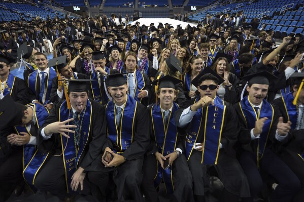 UCLA graduates from the class of 2024 pose for a photo prior to their commencement ceremony at Pauley Pavilion, Friday, June 14, 2024 in Los Angeles. (AP Photo/Damian Dovarganes)