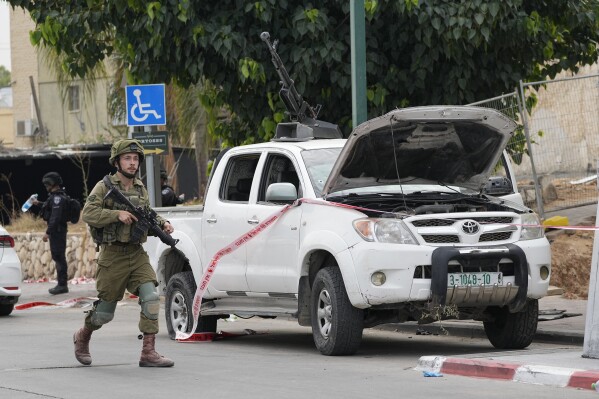 Israeli soldier walks by a pickup truck used by Palestinian militants in Sderot, Israel, on Saturday, Oct. 7, 2023. (AP Photo/Ohad Zwigenberg, File)
