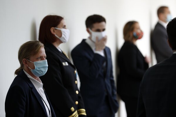 A member of the U.S. Secret Service, front, stands at her post wearing a mask as other staff member social distance wearing masks, before President Donald Trump speaks about the coronavirus during a press briefing in the Rose Garden of the White House, Monday, May 11, 2020, in Washington. (AP Photo/Alex Brandon)