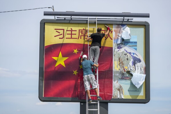 Workers stick a Chinese national flag on a billboard in Belgrade, Serbia, Tuesday, May 7, 2024. Chinese leader Xi Jinping's visit to European ally Serbia on Tuesday falls on a symbolic date: the 25th anniversary of the bombing of the Chinese Embassy in Belgrade during NATO's air war over Kosovo. (AP Photo/Darko Vojinovic)