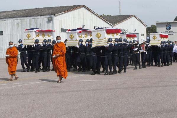 Thai Buddhist monks walk in front of coffins of victims from the Sunday night sinking of a Thai Navy warship as they were carried in a repatriation ceremony with religious rites in Prachuap Khiri Khan province, Thailand, Thursday, Dec. 22, 2022, before being flown to a Navy base in Sattahip district in eastern Chonburi province. The HTMS Sukhothai, a corvette in service for 35 years, sank Sunday night in rough seas with more than 100 people aboard. (AP Photo/Anuthep Cheysakron)