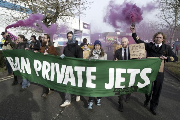 In this photo issued by Extinction Rebellion UK, climate activist Greta Thunberg, third right, takes part in a march to Farnborough Airport in southern England, Saturday Jan. 27, 2024. Greta Thunberg joined the march to protest the use of private jets and the expansion of an airport. Hundreds of local residents and activists holding banners and placards took part. (Extinction Rebellion UK via AP)
