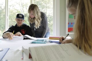 FILE - In this Oct. 9, 2019, photo, Donya Grant, center, works on a homeschool lesson with her son Kemper, 14, as her daughter Rowyn, 11, works at right, at their home in Monroe, Wash. The rate of households homeschooling their children doubled from the start of the pandemic last spring to the start of the new school year last September, according to a new U.S. Census Bureau report released this week. (AP Photo/Ted S. Warren, File)