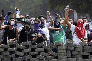 FILE - Protesters yell from behind the road block they erected as they face off with security forces near the University Politecnica de Nicaragua, UPOLI, in Managua, Nicaragua, Saturday, April 21, 2018. Nicaragua's National Assembly, controlled by President Daniel Ortega, outlawed four private universities on Wednesday, Feb. 2, 2022. Among the schools whose legal standing the assembly canceled was the UPOLI, which was a hotbed of antigovernment protests in 2018. (AP Photo/Alfredo Zuniga, File)