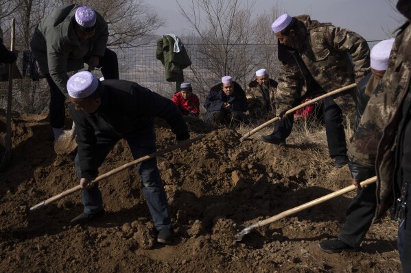 Ma Lianqiang, center, looks on as workers shovel earth into a grave where the body of his wife Han Suofeiya who was killed in an earthquake is lowered into a cemetery in Yangwa village near Dahejia town in northwestern China's Gansu province, Wednesday, Dec. 20, 2023. (AP Photo/Ng Han Guan)