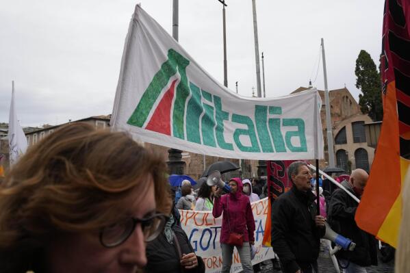 Alitalia workers gather with demonstrators during a transportation strike called by the COBAS union, in downtown Rome, Monday, Oct. 11, 2021. COBAS union, representing all public workers, called for a nation-wide strike to demand improved wages, work conditions, security and pensions. (AP Photo/Gregorio Borgia)