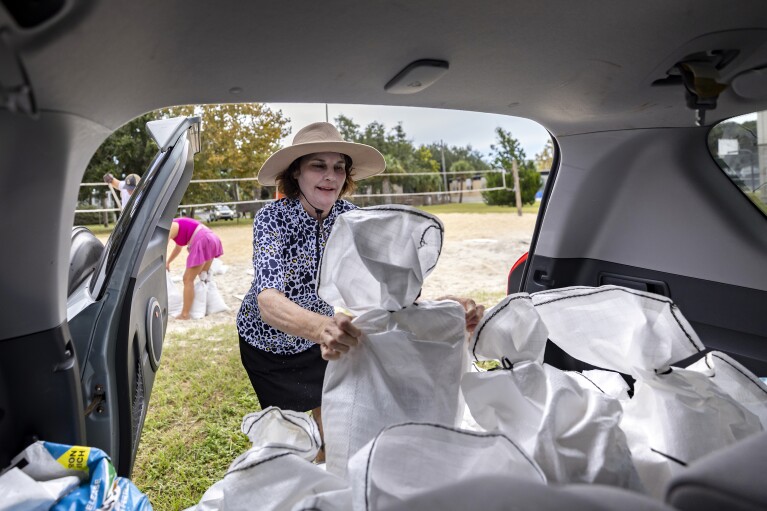 Tricia Bart Catalano lifts a sandbags into the back of her car, in preparation for Hurricane Idalia at Tybee Island, Ga., Tuesday, Aug., 29, 2023. Idalia strengthened into a hurricane Tuesday and barreled toward Florida's Gulf Coast. (Stephen B. Morton /Atlanta Journal-Constitution via AP)