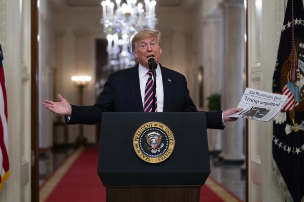 FILE - President Donald Trump holds up a newspaper with a headline that reads "Trump acquitted" during an event celebrating his impeachment acquittal, in the East Room of the White House, Feb. 6, 2020, in Washington. The impeachment investigation, sparked by a government whistleblower's complaint over Trump's call, swiftly became a milestone, the first in a generation since Democrat Bill Clinton faced charges over an affair with a White House intern. (APPhoto/Evan Vucci, File)