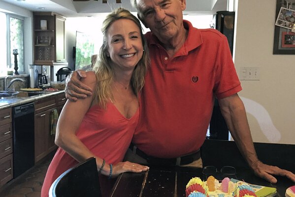 In this July 2019 photo, Tara Krebbs hugs her father, Charles Henry Krebbs, on his 74th birthday in Phoenix. He died from COVID-19 in August 2020. (Tara Krebbs via AP)
