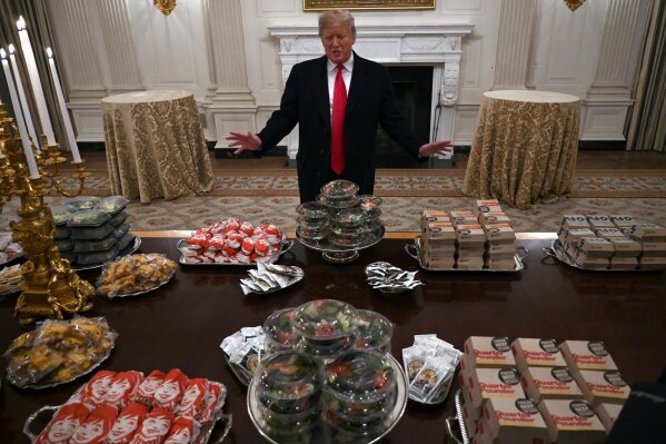 President Donald Trump talks to the media about the table full of fast food in the State Dining Room of the White House in Washington, Monday, Jan. 14, 2019, for the reception for the Clemson Tigers. (AP Photo/Susan Walsh)