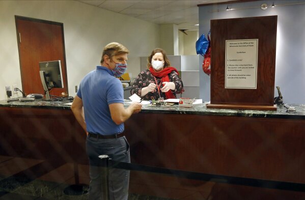 Face masks and social distancing were part of the process as election staffer Stella Hegg assists State Rep. Michael Howard as he files for re-election at the Secretary of State's Office Tuesday, May 19, 2020 in St. Paul, Minn. (AP Photo/Jim Mone)