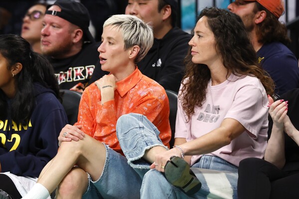 Megan Rapinoe, left, and Sue Bird, right, sit courtside during the second half of the WNBA basketball game between the Indiana Fever and the New York Liberty, Saturday, May 18, 2024, in New York. The New York Liberty won 91-80. (AP Photo/Noah K. Murray)
