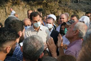 FILE - In this file photo released Oct. 13, 2020 on the official Facebook page of the Syrian Presidency, Syrian President Bashar Assad, center left, wearing a mask to help prevent the spread of the coronavirus, speaks with people during his tour of areas that suffered heavy damage from deadly wildfires, in the Syrian coastal province of Latakia. Syria executed 24 people Thursday, Oct. 21, 2021 after charging them with igniting wildfires last year that left three people dead and burnt thousands of hectares (acres) of forests, the Justice Ministry said. (Syrian Presidency via Facebook via AP, File)