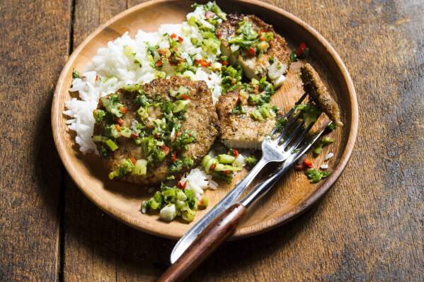 This image released by Milk Street shows a recipe for salt-and-pepper pork chops with spicy scallions. (Milk Street via AP)