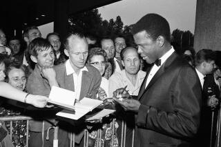 REMOVES REFERENCE TO THE BAHAMAS -FILE - Sidney Poitier signs autographs before the opening of the 14th International Film Festival at the West Berlin congress hall on June 26, 1964 in Berlin.  Poitier, the groundbreaking actor and enduring inspiration who transformed how Black people were portrayed on screen, became the first Black actor to win an Academy Award for best lead performance and the first to be a top box-office draw, died Thursday, Jan. 6, 2022. He was 94. (AP Photo/Edwin Reichert, File)