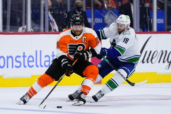 Philadelphia Flyers' Claude Giroux, left, and Vancouver Canucks' Jason Dickinson battle for the puck during the third period of an NHL hockey game, Friday, Oct. 15, 2021, in Philadelphia. (AP Photo/Matt Slocum)