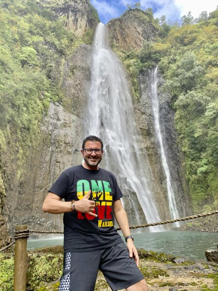 In this photo provided by Wissam Ali-Ahmad, Ali-Ahmad uses his phone to pose for a photo on Nov. 19, 2020, in Hanapepe, Hawaii. A group of Hawaii leaders is trying to attract more people like Ali-Ahmad to work remotely in Hawaii during the pandemic. (Wissam Ali-Ahmad via AP)