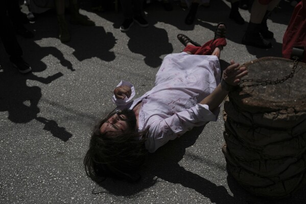 Charbel Joseph Antoun, 37, portraying Jesus, falls to the ground during a Good Friday reenactment of the crucifixion in Quraye, near the southern port city of Sidon, Lebanon, Friday, April 18, 2025. (AP Photo/Hassan Ammar)