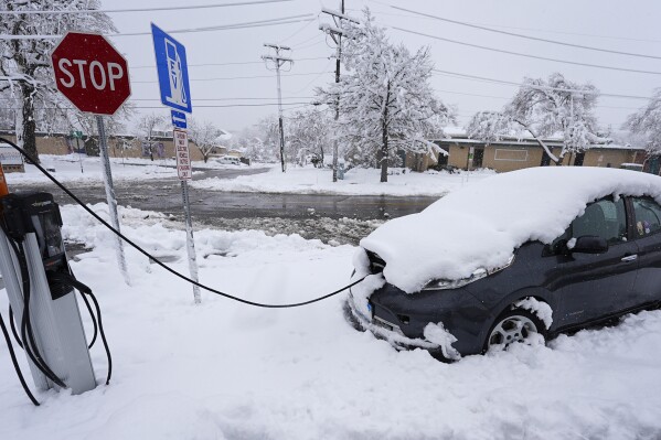 An electric Nissan Leaf gets a charge at a station as a late winter storm dropped up to a foot of snow Thursday, March 14, 2024, in Golden, Colo. Forecasters predict that the storm will persist until early Friday, snarling traffic along Colorado's Front Range communities. (AP Photo/David Zalubowski)