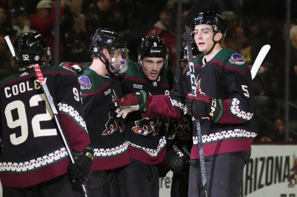 Arizona Coyotes center Nick Schmaltz (8) celebrates after his goal against the Washington Capitals with center Logan Cooley (92), defensemen Juuso Valimaki, second from left, and Nick Schmaltz (8) during the first period of an NHL hockey game Monday, Dec. 4, 2023, in Tempe, Ariz. (APPhoto/Ross D. Franklin)