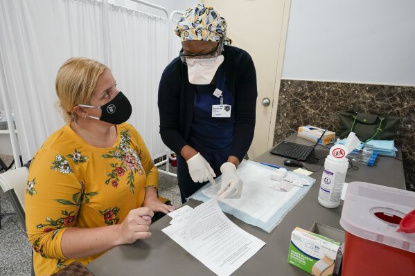 A Northwell Health registered nurse goes over the paper work with mosque member Zejreme Rodoncic after inoculating her with the Johnson & Johnson COVID-19 vaccine at a pop up vaccinations site the Albanian Islamic Cultural Center, Thursday, April 8, 2021, in the Staten Island borough of New York.  Ahead of Ramadan, Islamic leaders are using social media, virtual town halls and face-to-face discussions to spread the word that it’s acceptable for Muslims to be vaccinated during daily fasting that happens during the holy month. (AP Photo/Mary Altaffer)