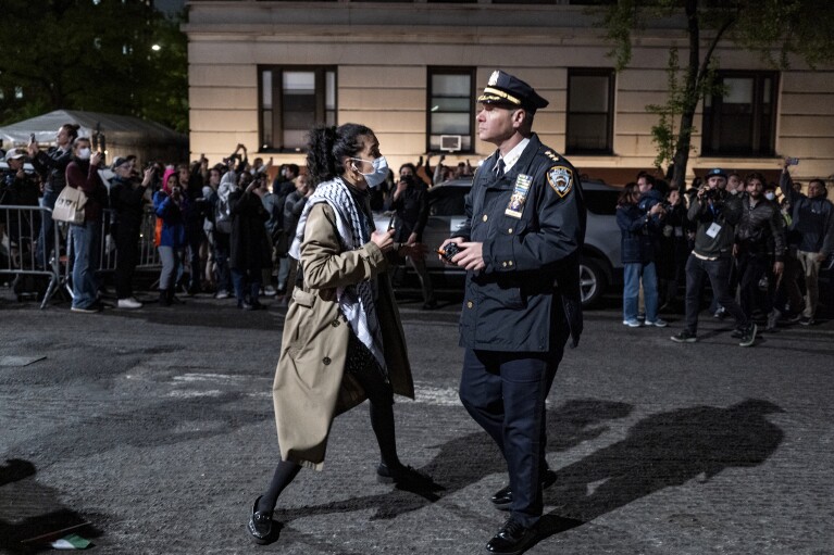 A person engages with a New York City police official as he, along with other officers, move to clear a main gate at Columbia University in New York on Tuesday, April 30, 2024, as authorities cleared parts of the campus of protesters after a building was taken over by activists earlier in the day. (AP Photo/Craig Ruttle)