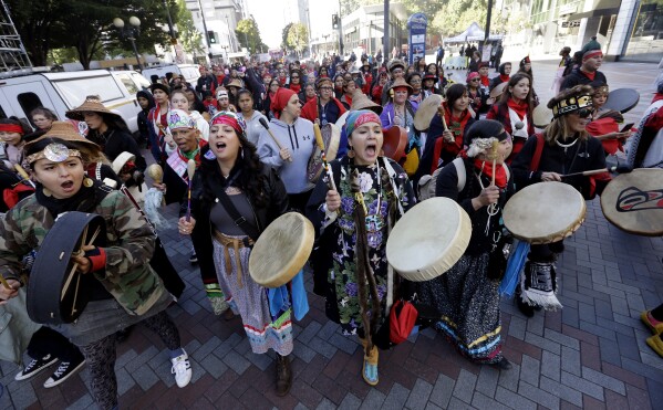 FILE - Women drummers sing as they lead a march during an Indigenous Peoples Day event, Oct. 9, 2017, in Seattle. Native American people will celebrate their centuries-long history of resilience on Monday, Oct. 9, 2023, through ceremonies, dances and speeches. The events across the United States will come two years after President Joe Biden officially commemorated Indigenous Peoples Day. (AP Photo/Elaine Thompson, File)