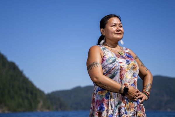 Jeanette Kiokun, the tribal clerk for the Qutekcak Native Tribe in Seward, Alaska, poses for a portrait on the shore of Lake Crescent at NatureBridge in the Olympic National Park during the 2023 Tribal Climate Camp, Thursday, Aug. 17, 2023, near Port Angeles, Wash. (AP Photo/Lindsey Wasson)
