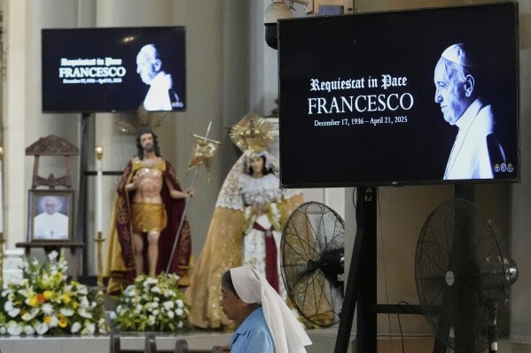 Images of the late Pope Francis is shown as a Catholic nun walks inside a church in Quezon city, Philippines Monday, April 21, 2025. (AP Photo/Aaron Favila)