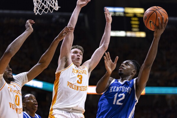 Kentucky guard Antonio Reeves (12) shoots as he is defended by Tennessee guard Dalton Knecht (3) and forward Jonas Aidoo (0) during the second half of an NCAA college basketball game Saturday, March 9, 2024, in Knoxville, Tenn. (AP Photo/Wade Payne)