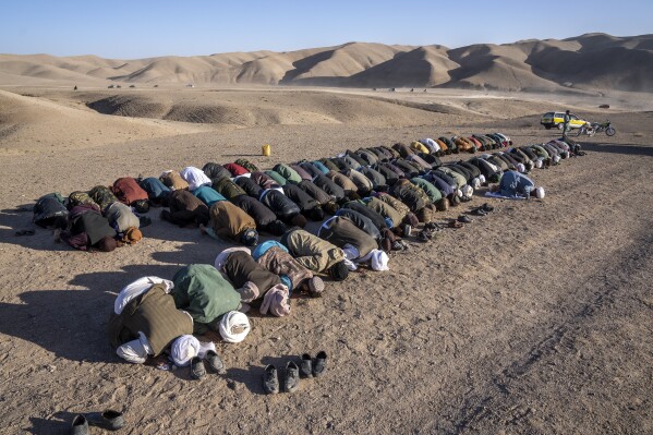 Afghans pray for relatives killed in an earthquake at a burial site in Zenda Jan district in Herat province, western of Afghanistan, Sunday, Oct. 8, 2023. Powerful earthquakes killed at least 2,000 people in western Afghanistan, a Taliban government spokesman said Sunday. It's one of the deadliest earthquakes to strike the country in two decades. (AP Photo/Ebrahim Noroozi)