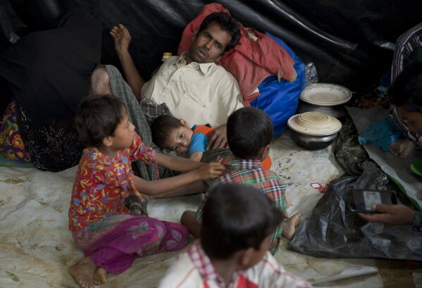 
              In this Saturday, Jan. 13, 2018, photo, a newly arrived Rohingya family rests together in a transit camp in the Nayaprar refugee camp near Cox's Bazar, Bangladesh. Rohingya Muslims, who have been loathed by Myanmar’s Buddhist majority for decades, are locked down in their villages _ sometimes even in their homes _ and prevented from farming, fishing, foraging, trade and work. The Myanmar government denies ethnic cleansing and says it is battling terrorists. (AP Photo/Manish Swarup)
            