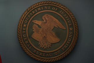 The seal for the Federal Bureau of Prisons is seen at Federal Bureau of Prisons headquarters in Washington, Oct. 24, 2022. A federal prison inmate was able to obtain a firearm at a prison in Arizona and then pulled it out in a visitation room and pointed it at a visitor's head. The Associated Press has learned the  weapon misfired and the female visitor was uninjured in the Nov. 13, incident at the Federal Correctional Institution in Tucson. (AP Photo/Carolyn Kaster, File)