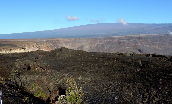 FILE - Hawaii's Mauna Loa volcano, background, towers over the summit crater of Kilauea volcano in Hawaii Volcanoes National Park on the Big Island on April 25, 2019. A magnitude 5.7 earthquake struck the world's largest active volcano Friday, Feb. 9, 2024, Mauna Loa on the Big Island of Hawaii, knocking items off shelves in nearby towns but not immediately prompting reports of serious damage. (APPhoto/Caleb Jones, File)