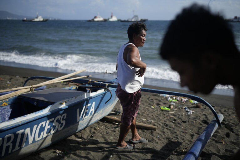 Joseph Vargas, president of a fishing association, walks along the shore at the coastal village of Santa Clara where his home sits near a liquified natural gas power plant in Batangas province, Philippines on Tuesday, Aug. 8, 2023. The Philippines is seeing one of the world's biggest buildouts of natural gas infrastructure. Vargas says most communities have seen no benefit from the power plants built so far. (AP Photo/Aaron Favila)