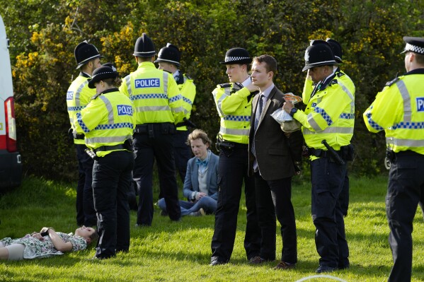 FILE - Members of the police detain protesters as activists tried to block the start of the Grand National horse race at Aintree Racecourse Liverpool, England, on April 15, 2023. There will be a new look to the ever-adapting Grand National Steeplechase this year. Organizers of Britain’s biggest horse race have taken action to improve safety and avoid a repeat of the chaos sparked by animal-rights activists before last year’s edition. Among the changes coming into effect for Saturday's race are the field being trimmed to 34 horses in an attempt to reduce collisions and bunching either side of the huge fences. (AP Photo/Jon Super, File)