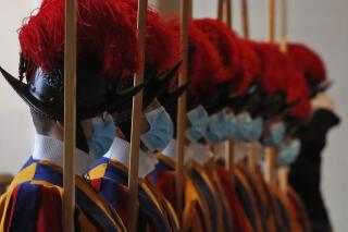 FILE - In this Saturday, Oct. 24, 2020 file photo, Vatican Swiss Guards wear masks to curb the spread of COVID-19 as they stand attention at the Vatican. Three Vatican Swiss Guards who have refused to be vaccinated against COVID-19 upon Holy See orders and have left the storied corps to return to Switzerland. A Swiss Guard official, Lt. Urs Breitenmoser told The Associated Press on Sunday all Swiss Guards were asked to be vaccinated “to protect their health and that of the others they come into contact as part of their service.” (AP Photo/Alessandra Tarantino, File)