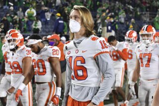 FILE - In this Saturday, Nov. 7, 2020 file photo, Clemson quarterback Trevor Lawrence (16) leaves the field with his teammates after Clemson lost to Notre Dame 47-40 in two overtimes during an NCAA college football game in South Bend, Ind. As virus disruptions mount and the Dec. 19 end of college football's regular season draws closer, the possibility grows that conference championships, major awards and even College Football Playoff participants will be determined by COVID-19. (Matt Cashore/Pool Photo via AP, File)