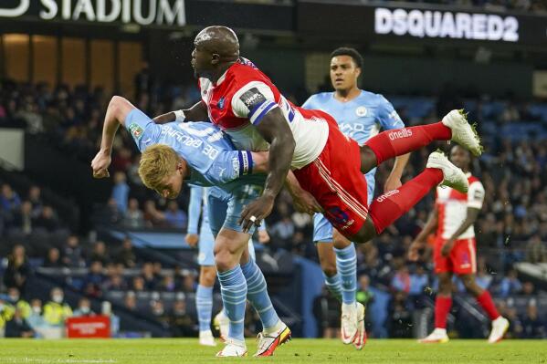 Manchester City's Kevin De Bruyne, left, and Wycombe Wanderers Adebayo Akinfenwa collide as they compete for the ball during the English League Cup third round soccer match between Manchester City and Wycombe Wanderers at Etihad Stadium, in Manchester England, Tuesday, Sept. 21, 2021. (AP Photo/Dave Thompson)