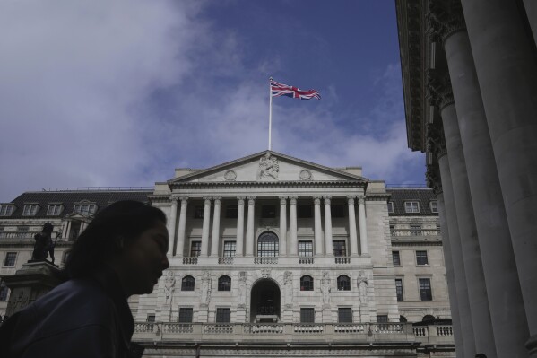 FILE - A woman walks in front of the Bank of England, at the financial district in London, on March 23, 2023. The Bank of England is widely expected to indicate Thursday March 21, 2024 that interest rates could be cut in the coming months following news that inflation across the U.K. is falling faster than expected. (AP Photo/Kin Cheung, File)
