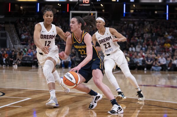 Indiana Fever's Caitlin Clark (22) goes to the basket against Atlanta Dream's Nia Coffey (12) and Aerial Powers (23) during the second half of a WNBA preseason basketball game Thursday, May 9, 2024, in Indianapolis. (AP Photo/Darron Cummings)