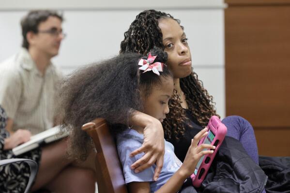 Philana Holmes and her daughter Olivia Caraballo, 7 listen to the final witness in their case at the Broward County Courthouse in Fort Lauderdale on Wednesday May 10, 2023. McDonald’s and a franchise holder are at fault after a hot Chicken McNugget from a Happy Meal fell on the girl's leg and caused second-degree burns, a jury in South Florida has found, Thursday, May 11. (Mike Stocker/South Florida Sun-Sentinel via AP)