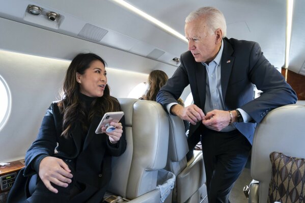 In this photo taken in November 2019, former Vice President Joe Biden speaks with his traveling national press secretary, Remi Yamamoto, on a flight to South Carolina. Richard Grenell, President Donald Trump's former ambassador to Germany and former acting director of national intelligence, tweeted this photo on Sunday, Nov. 1, 2020, alongside a photo of Biden standing outdoors while wearing a mask. The tweet, which claims that Biden wears a mask outside but doesn't wear one on his plane, creates the false impression that this photo of Biden without a mask was taken during the coronavirus pandemic. (Adam Schultz/Biden for President via AP)