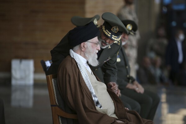 In this picture released by the official website of the office of the Iranian supreme leader, Supreme Leader Ayatollah Ali Khamenei, left, listens to army commander Gen. Abdolrahim Mousavi during a graduation ceremony for a group of armed forces cadets in Tehran, Iran, Tuesday, Oct. 10, 2023. (Office of the Iranian Supreme Leader via AP)