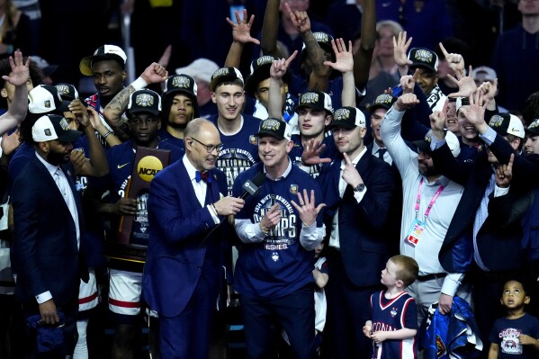 UConn head coach Dan Hurley, center, and his players celebrate after the NCAA college Final Four championship basketball game against Purdue, Monday, April 8, 2024, in Glendale, Ariz. (AP Photo/Ross D. Franklin)