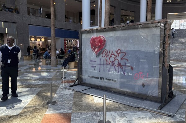 A slab of wall art, The "Battle to Survive a Broken Heart,' created by the artist Banksy, sits on display inside the Brookfield Place atrium, Tuesday, April 29, 2025, in New York. The nearly four-ton piece will be auctioned off on May 21. (AP Photo/Julie Jacobson)